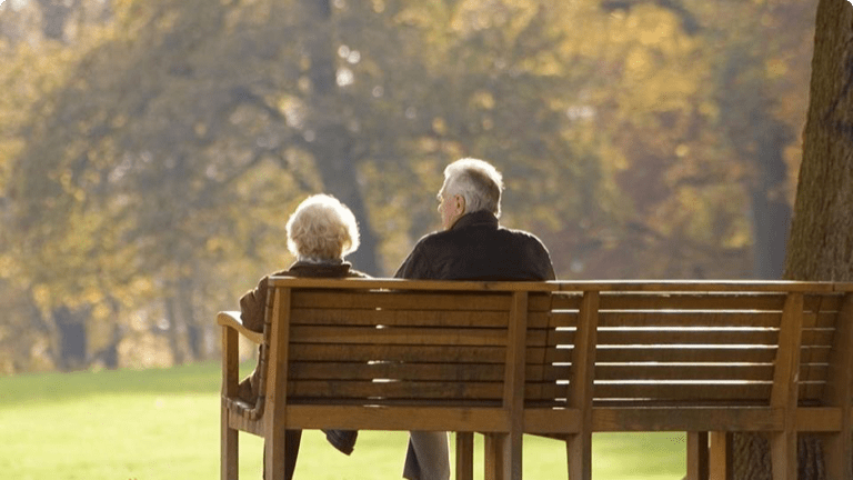 Elderly couple sitting together on a bench in a park Elderly couple sitting together on a bench in a park
