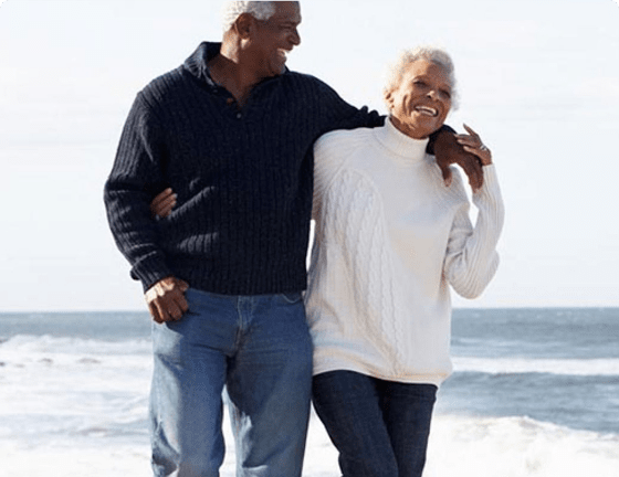 Elderly couple strolling along beach laughing together Elderly couple strolling along beach laughing together