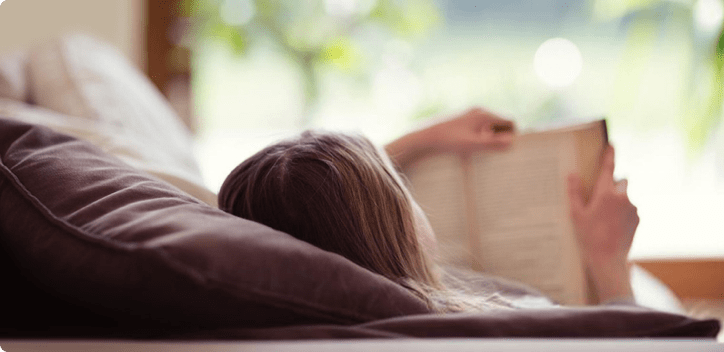 Woman reading a book whilst laying down Woman reading a book whilst laying down